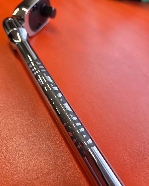 A close-up of a chrome ratchet handle fiber-engraved with an owner's name along the shaft.