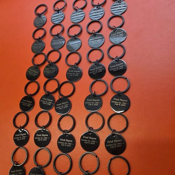 Rows of memorial keyrings, each tag engraved Fred Hayes with his dates.
