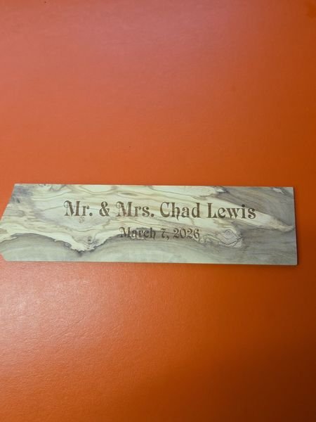 A slim olive-wood plaque engraved Mr. and Mrs. Chad Lewis, March 7 2026.