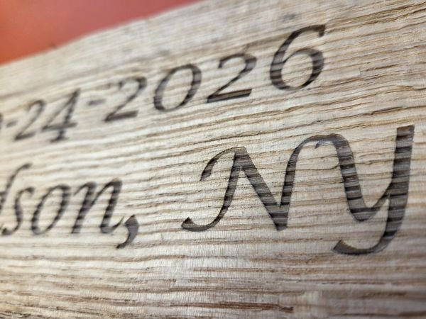 A macro view of engraved barn wood, the date and Hudson, NY cut into the weathered grain.