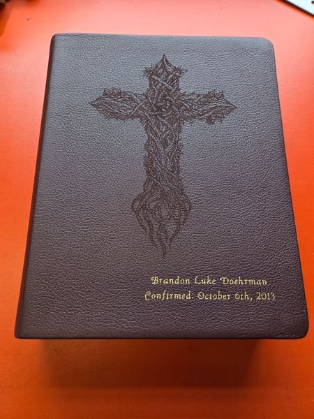 A brown leather-bound Bible engraved with a thorn-branch cross above the words Brandon Luke Doehrman, Confirmed October 6th 2013.