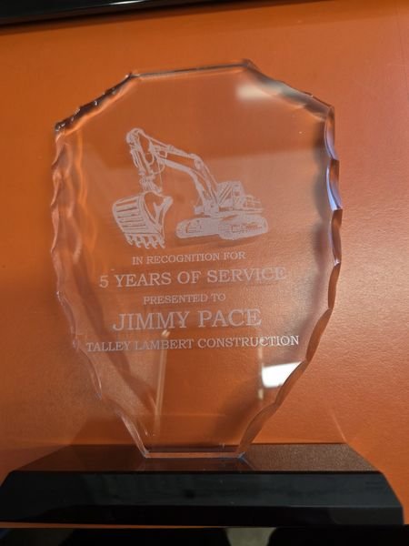 A faceted glass award on a black base, engraved with an excavator above the words In Recognition For 5 Years Of Service, Presented To Jimmy Pace, Talley Lambert Construction.