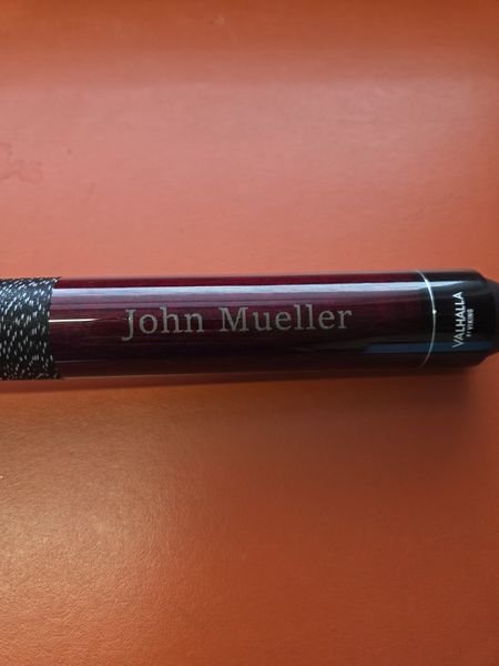 A Valhalla by Viking pool cue engraved with the name John Mueller along its burgundy butt, above the linen wrap.