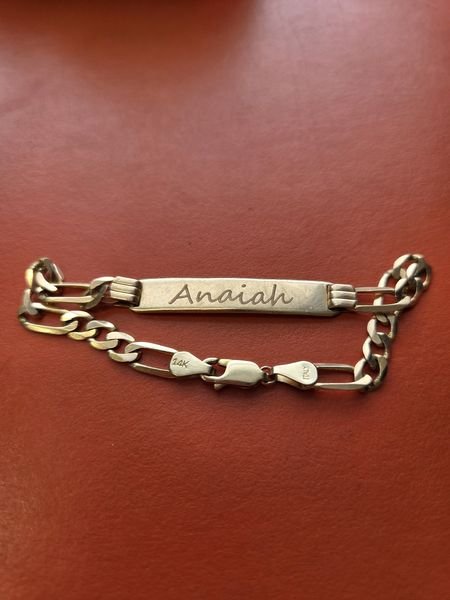 A 14K gold Figaro-link ID bracelet engraved in flowing script with the name Anaiah.