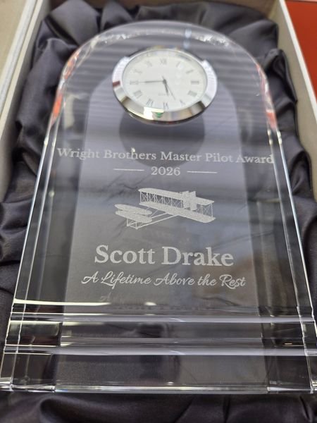 A close-up of the crystal clock award, the Wright Flyer etched beneath the dial above Scott Drake, A Lifetime Above the Rest.