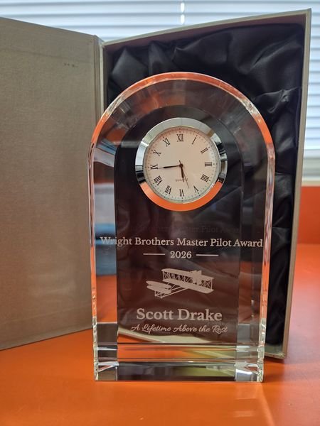 The Scott Drake Master Pilot crystal clock award standing in front of its open presentation box.