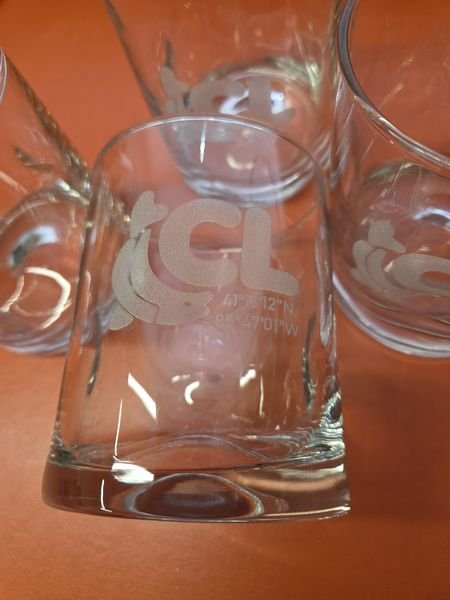 A set of rocks glasses etched with the CL logo, a curled fish, and the coordinates 41°17'12"N 85°47'01"W.