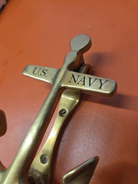 A close-up of the brass anchor knocker, the words U.S. Navy engraved crisp and dark into the polished stock.