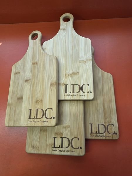A stack of bamboo paddle cutting boards each engraved with the LDC Louis Dreyfus Company logo.