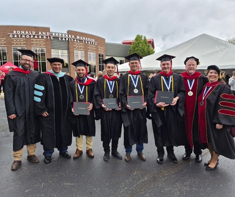 Graduates and faculty in robes posed outside the Manahan Orthopaedic Capital Center.